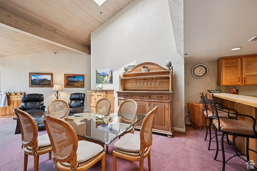 Carpeted dining area featuring a textured wall, wood ceiling, and vaulted ceiling