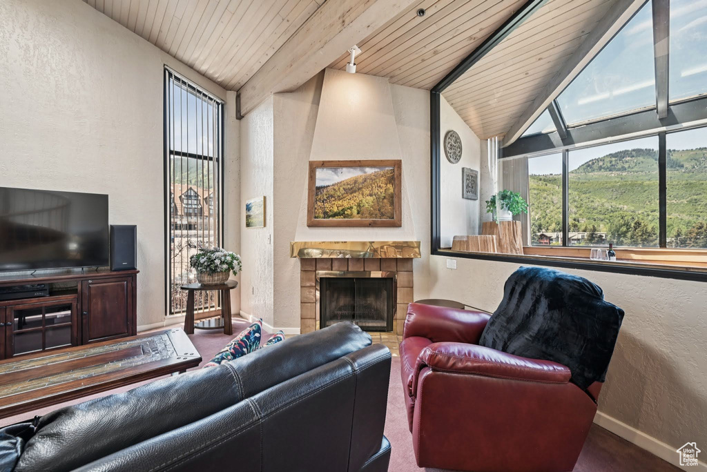 Living area with wood ceiling, a textured wall, and a tiled fireplace