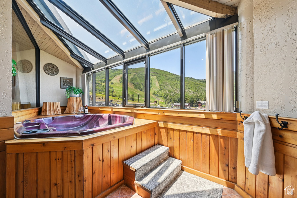 Bathroom with vaulted ceiling, a textured wall, and wooden walls