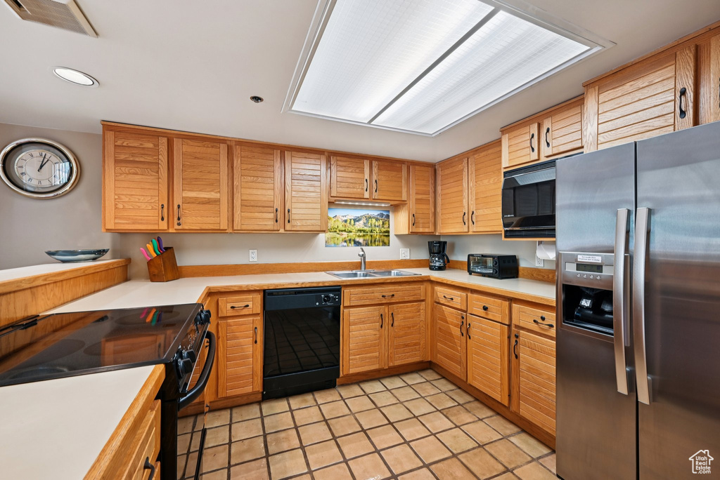 Kitchen featuring black appliances, light countertops, light tile patterned flooring, and recessed lighting
