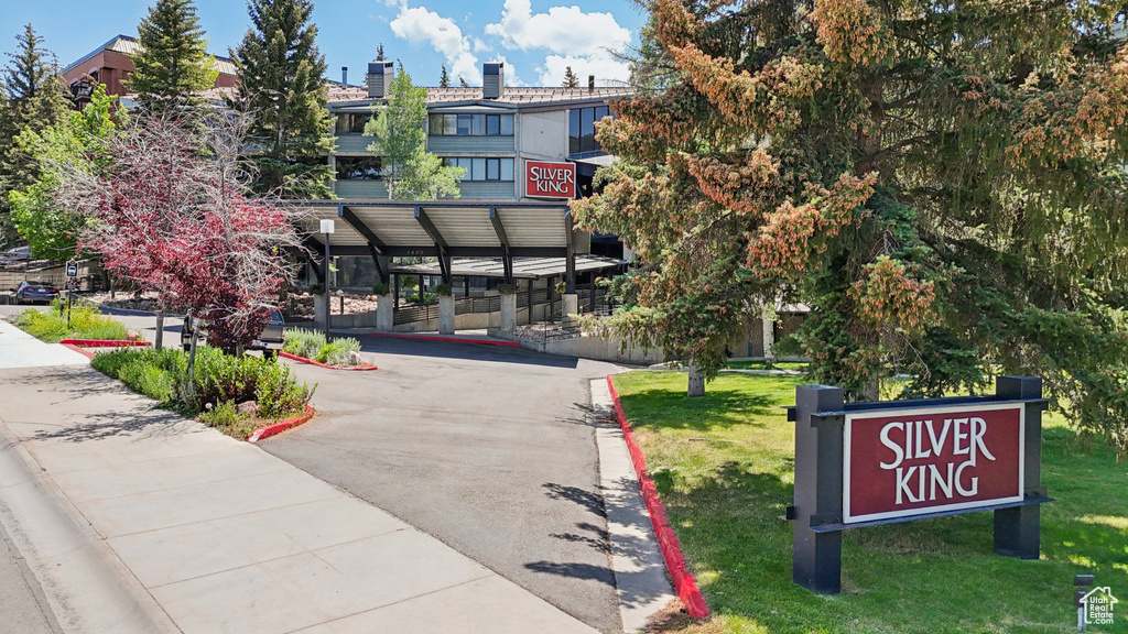 Surrounding community with asphalt driveway, a yard, and a carport