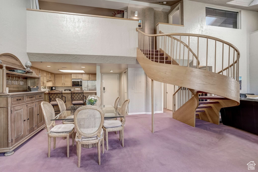 Dining space with light carpet, stairs, and a towering ceiling