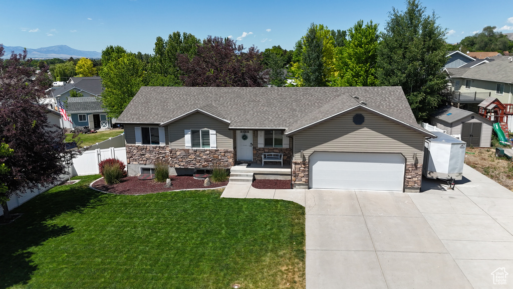 Ranch-style home featuring an attached garage, concrete driveway, stone siding, a porch, and roof with shingles