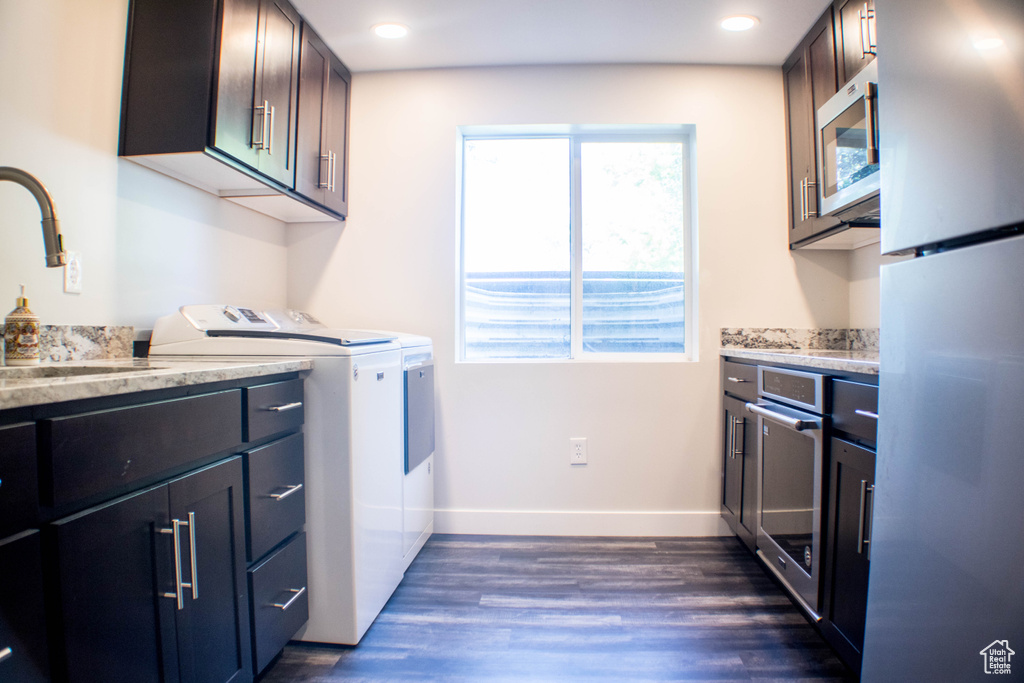 Washroom with separate washer and dryer, dark wood finished floors, cabinet space, and recessed lighting
