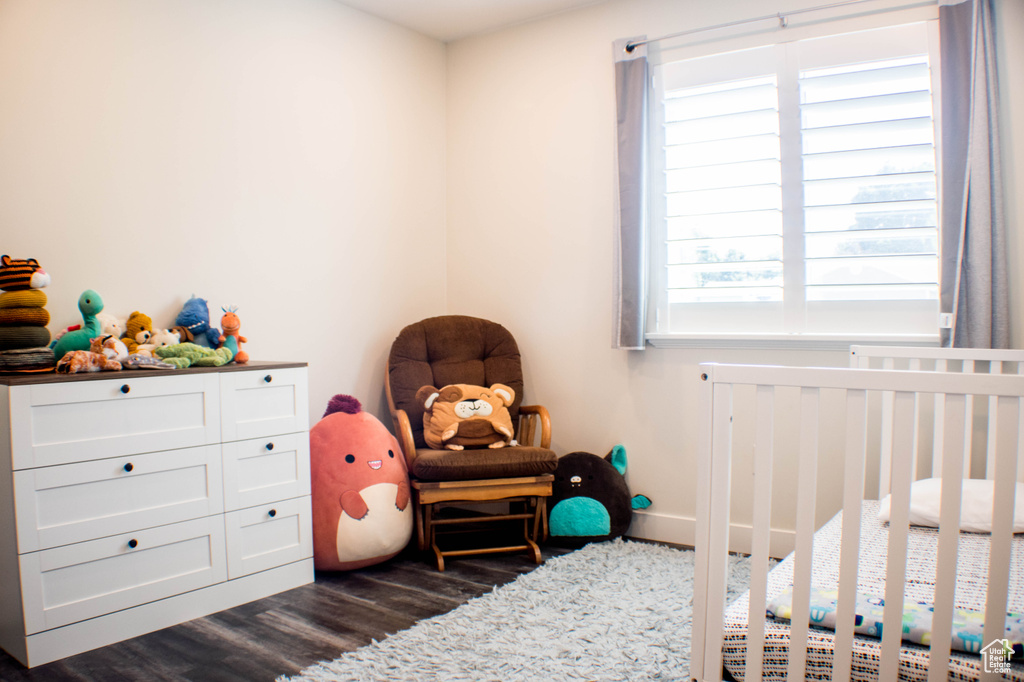 Bedroom featuring a crib and dark wood finished floors