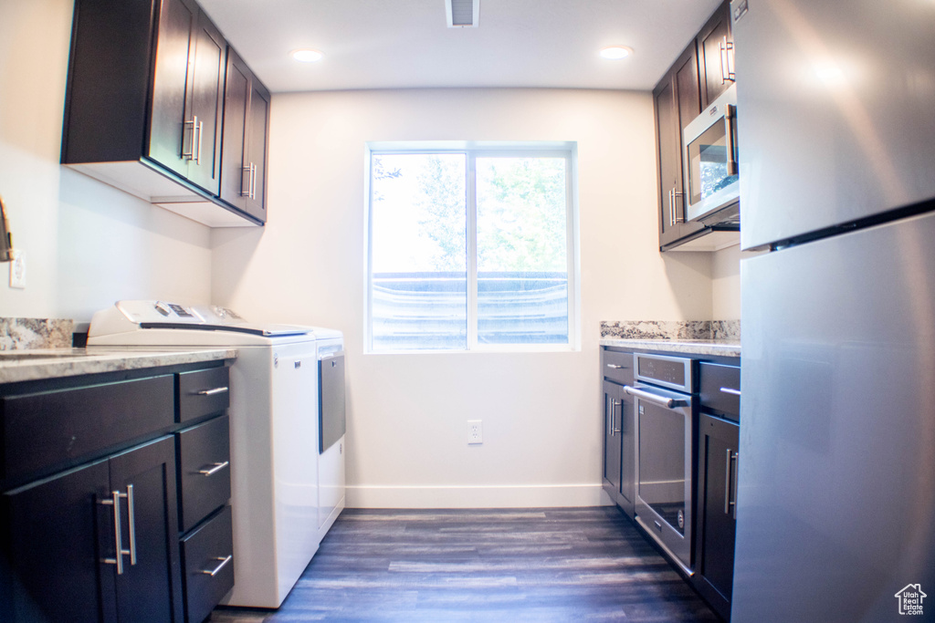 Laundry room featuring dark wood finished floors, washing machine and dryer, cabinet space, and recessed lighting