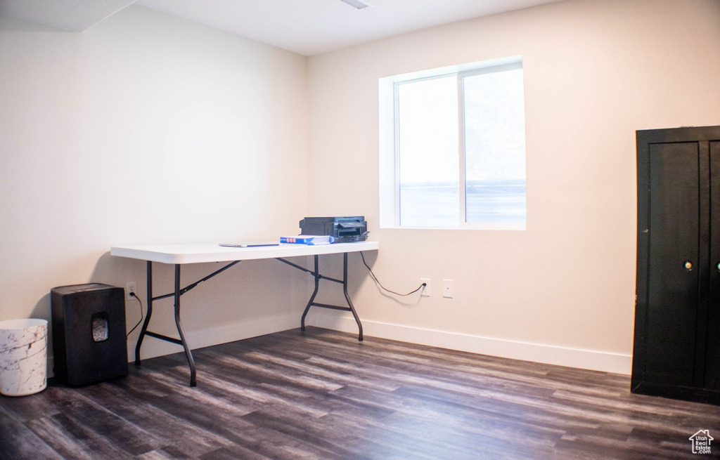 Office area with dark wood-style flooring and baseboards