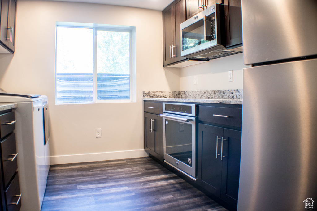 Kitchen featuring stainless steel appliances, plenty of natural light, dark wood-type flooring, and washer / dryer