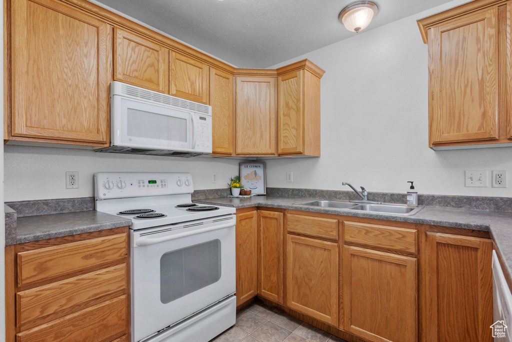 Kitchen with white appliances, dark countertops, and light tile patterned floors