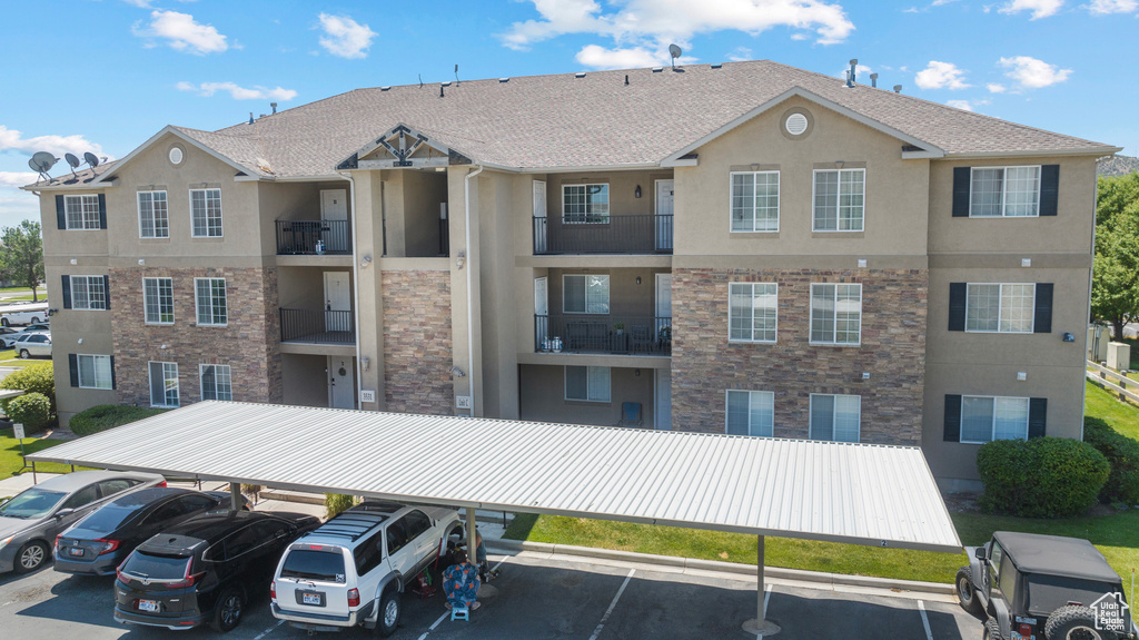View of apartment building / complex featuring covered and uncovered parking