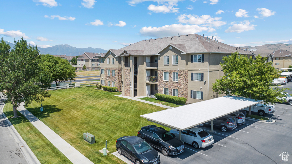 View of property with covered and uncovered parking, a mountain view, and a residential view