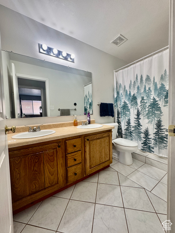 Bathroom with double vanity, tile patterned flooring, a textured ceiling, and a shower with shower curtain