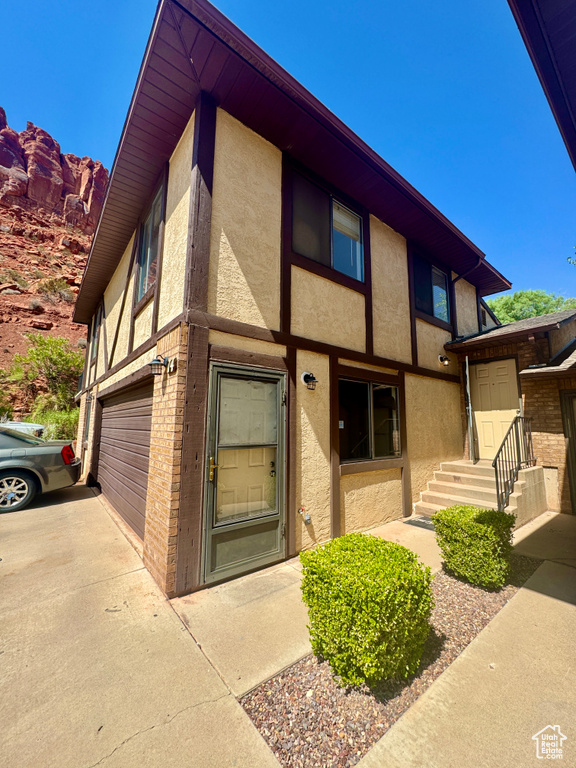 View of front facade featuring stucco siding, an attached garage, and driveway