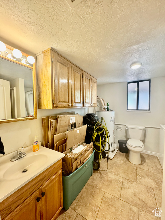 Bathroom featuring electric water heater, vanity, and a textured ceiling