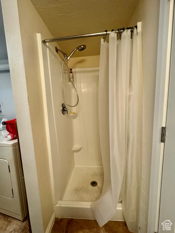 Full bath featuring washer / clothes dryer, a textured ceiling, and a shower stall