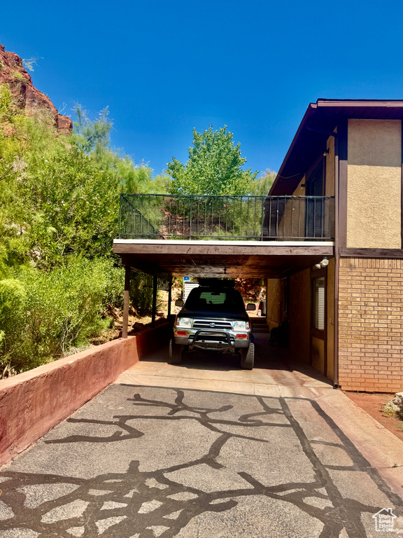 View of parking / parking lot with driveway and a carport