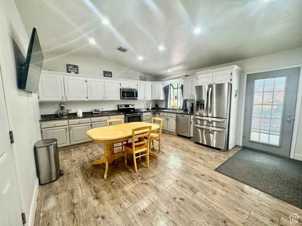 Kitchen with stainless steel appliances, dark countertops, recessed lighting, light wood-style flooring, and white cabinetry