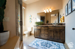 Bathroom with vanity, a shower with shower door, a chandelier, and tile patterned floors