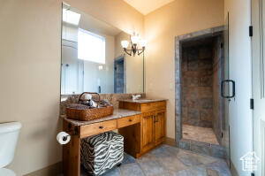 Bathroom with a chandelier, double vanity, and a shower stall