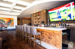 Community bar area with coffered ceiling, wood finished floors, and beam ceiling