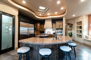 Kitchen featuring a large island with sink, custom exhaust hood, recessed lighting, a kitchen bar, and built in shelves