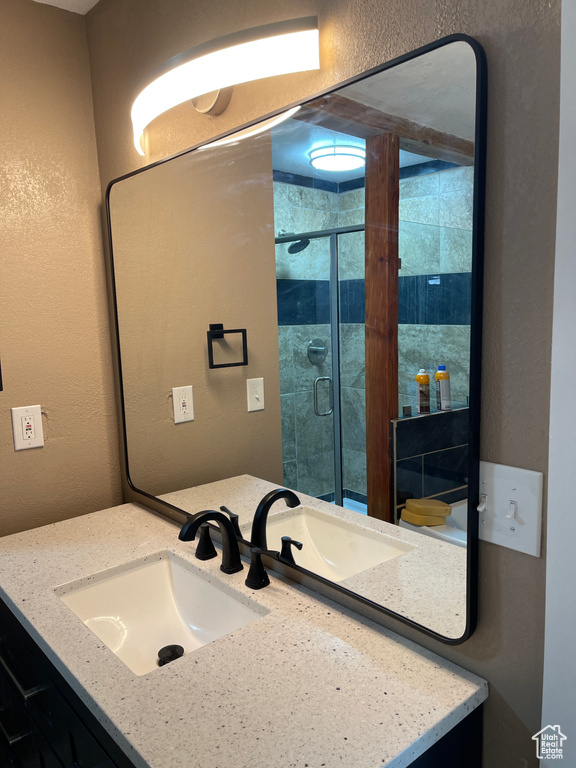 Full bath featuring vanity, a stall shower, and a textured wall