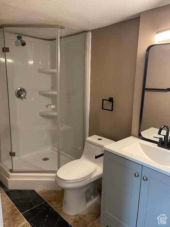 Full bath featuring a textured ceiling, vanity, and a shower stall