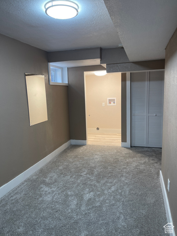 Below grade area featuring a textured ceiling and carpet flooring