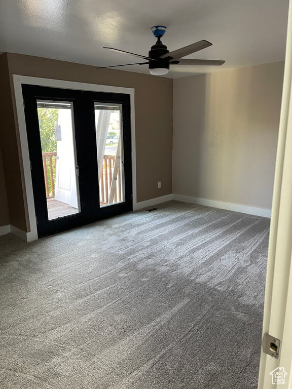 Empty room featuring a ceiling fan and carpet