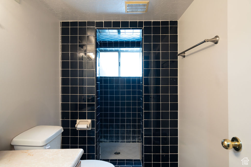 Bathroom featuring tiled shower and vanity