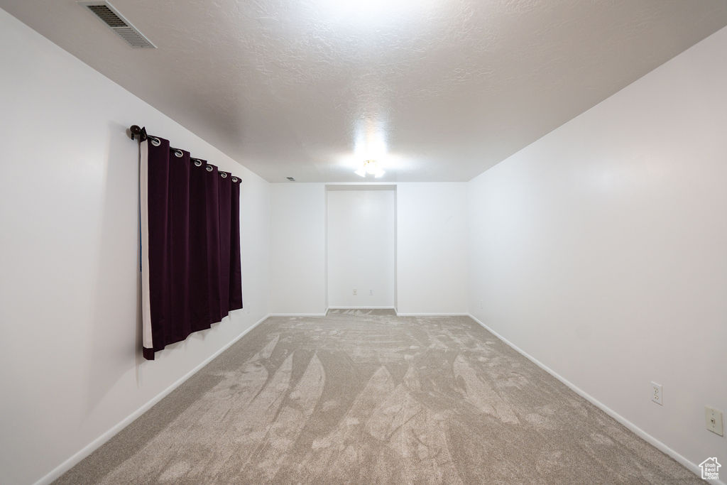 Spare room featuring light colored carpet and a textured ceiling