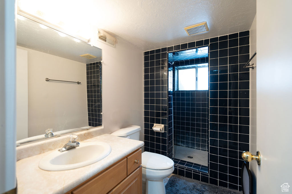 Full bathroom featuring a tile shower, vanity, and a textured ceiling
