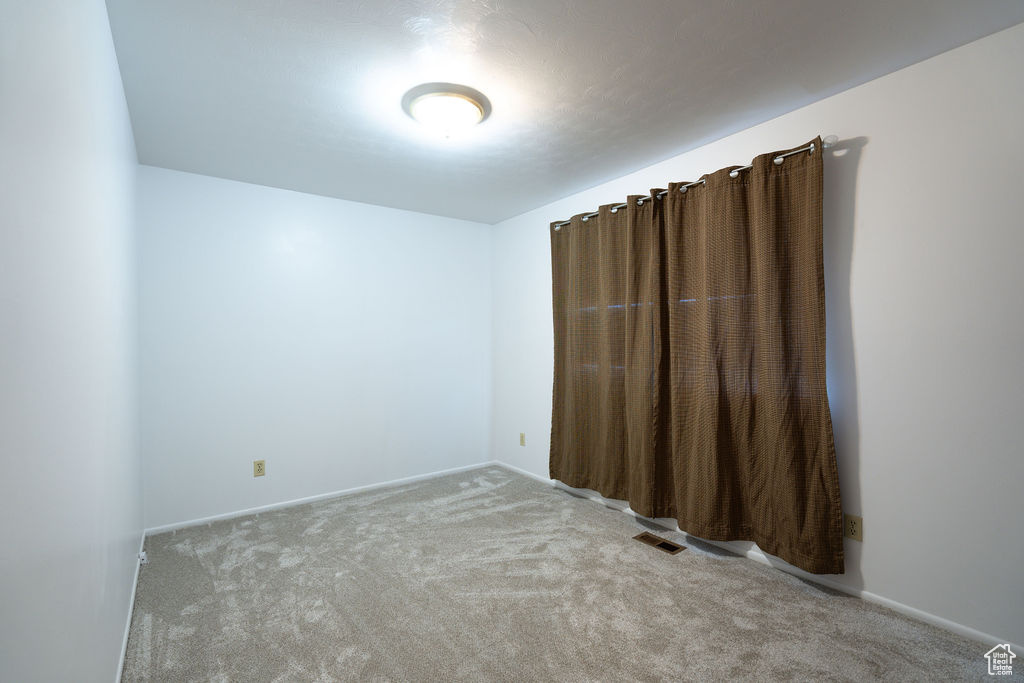 Carpeted spare room featuring baseboards