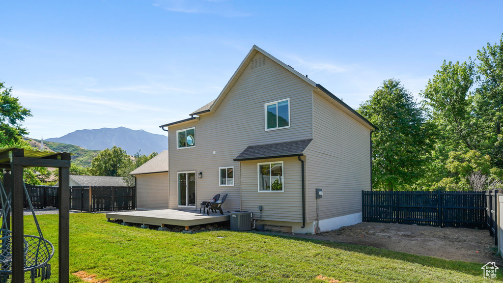 Back of property with a fenced backyard and a deck with mountain view