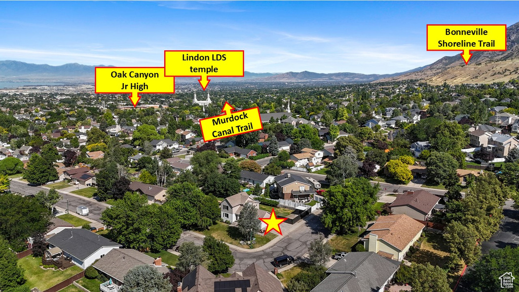 Aerial view of property and surrounding area featuring mountains and nearby suburban area