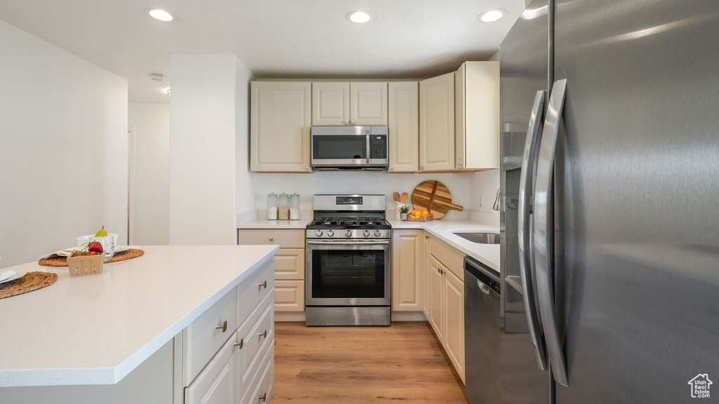 Kitchen featuring appliances with stainless steel finishes, light countertops, light wood-type flooring, and recessed lighting