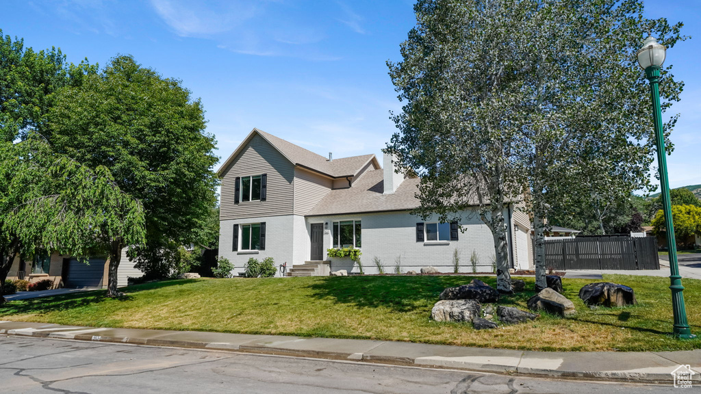 Traditional-style house with a front lawn, brick siding, and roof with shingles
