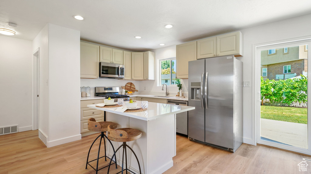 Kitchen with stainless steel appliances, light wood-style floors, light countertops, a breakfast bar area, and recessed lighting