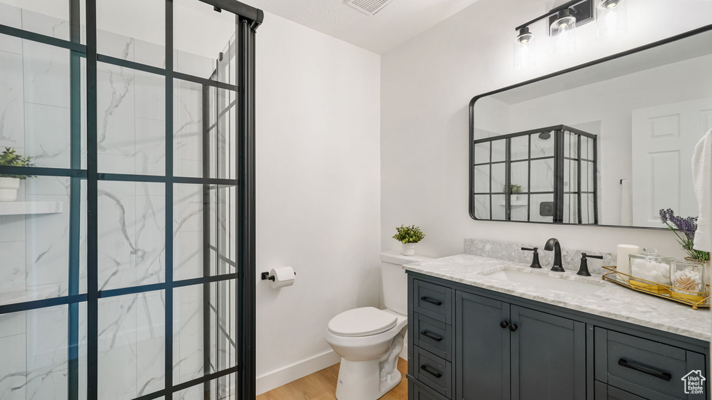 Bathroom with a shower stall, vanity, and wood finished floors
