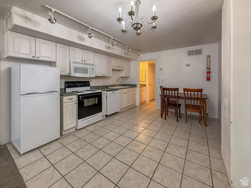 Kitchen featuring white appliances, light tile patterned floors, a chandelier, white cabinetry, and rail lighting