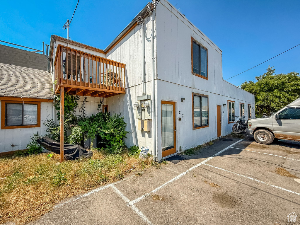 View of side of property with uncovered parking and a balcony