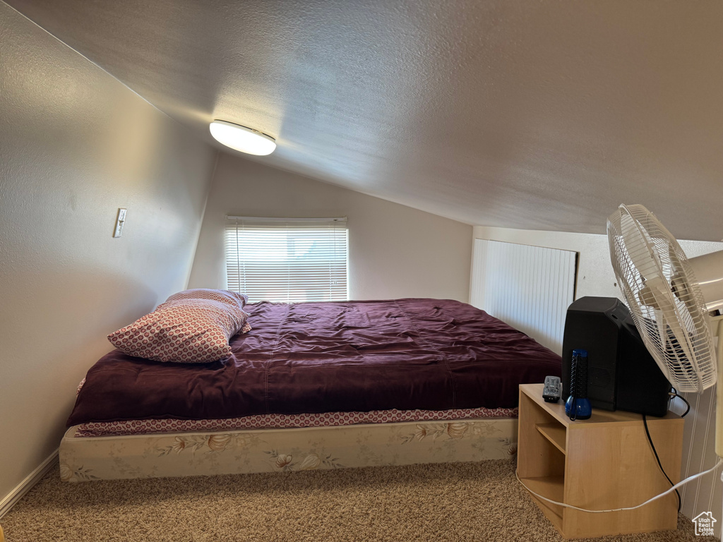 Bedroom featuring lofted ceiling, carpet flooring, and a textured ceiling