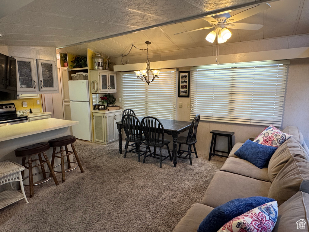 Dining area featuring carpet flooring, lofted ceiling, a ceiling fan, and a chandelier