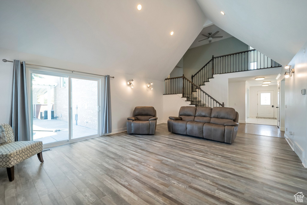 Living area featuring wood finished floors, stairs, high vaulted ceiling, ceiling fan, and recessed lighting