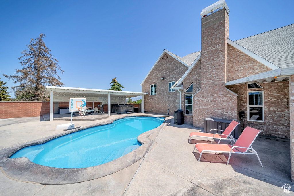 View of pool featuring a hot tub, a patio area, and a fenced backyard