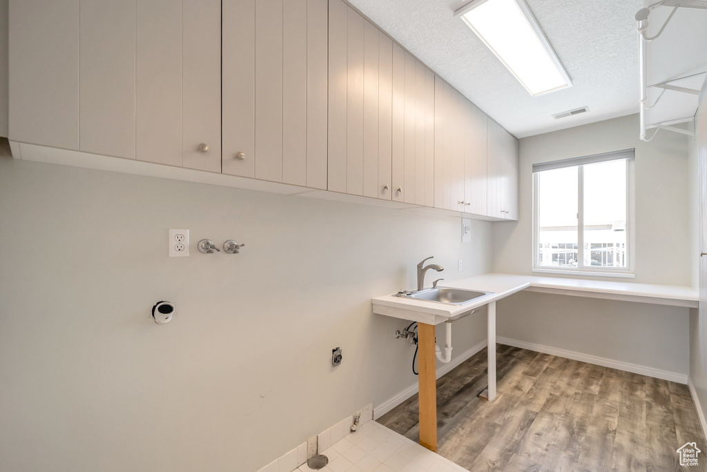 Laundry area featuring cabinet space, gas dryer hookup, hookup for an electric dryer, and light wood-type flooring