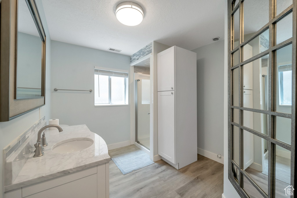 Full bath featuring a stall shower, vanity, and wood finished floors