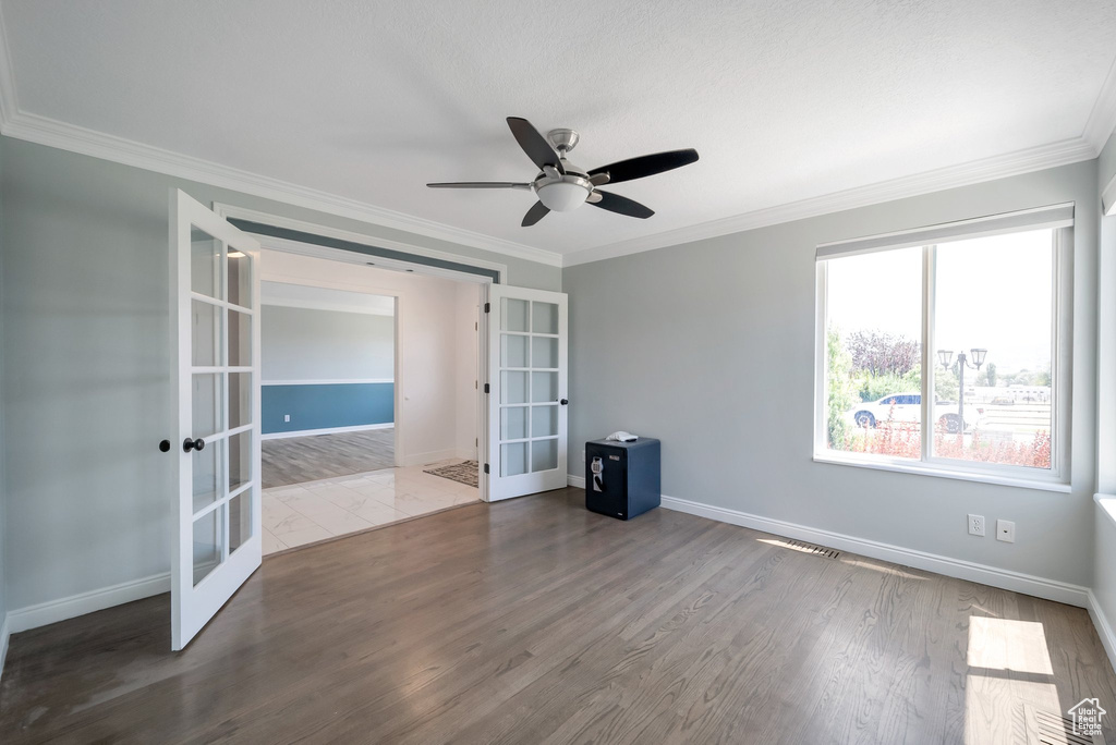Unfurnished room with french doors, wood finished floors, crown molding, and a ceiling fan