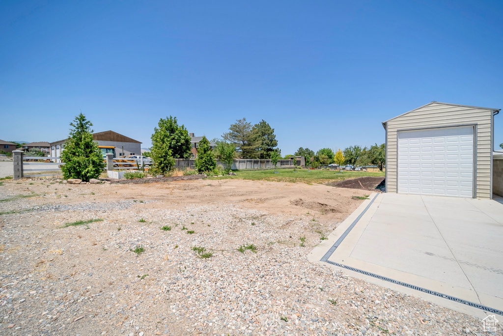 View of yard with concrete driveway, an outbuilding, and a garage