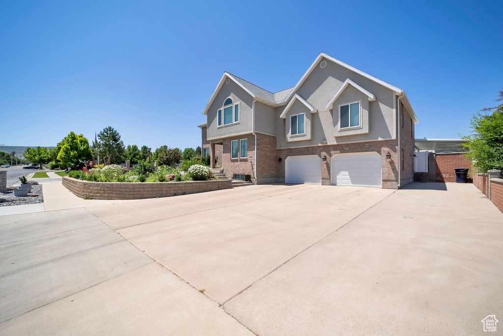 View of front of house with a garage, driveway, and stucco siding